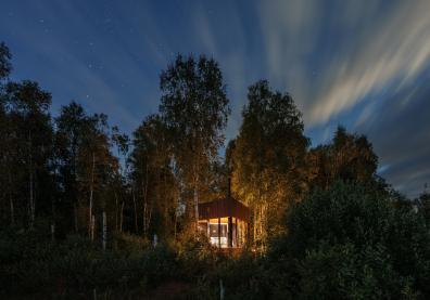 Cabane en bois éclairée au milieu d'une forêt 