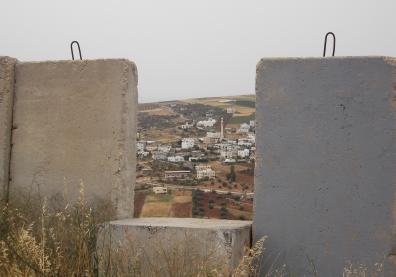 Vue d'un paysage d'habitations en Palestine avec en premier plan un mur 