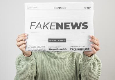 Quelqu'un tient un journal devant son visage avec l'inscription "fake news"