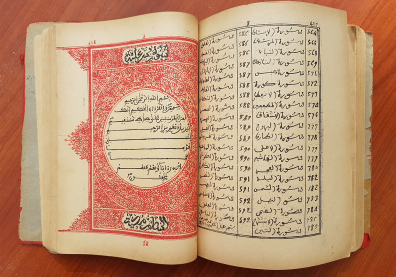 Ecritures arabes sur un livre ouvert sur deux pages avec sur la page de gauche une arabesque rouge