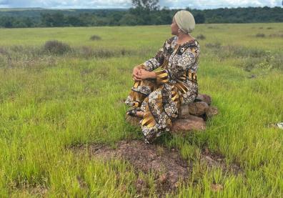 Une femme, isolée dans un espace indéfini et tournée vers un horizon certes dégagé mais surplombé par des nuages épais