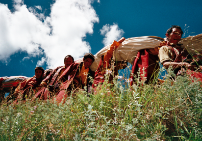 Des moines tibétains marchent dans la nature et portent sur leur dos un grand tissu
