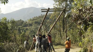 Des hommes dans une forêt hissent une structure en bois