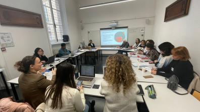 Un groupe de personne est installé dans une salle de classe en carrés avec une présentation powerpoint au tableau