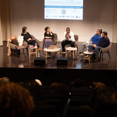 Plusieurs intervenants discutent sur la scène de l'auditorium