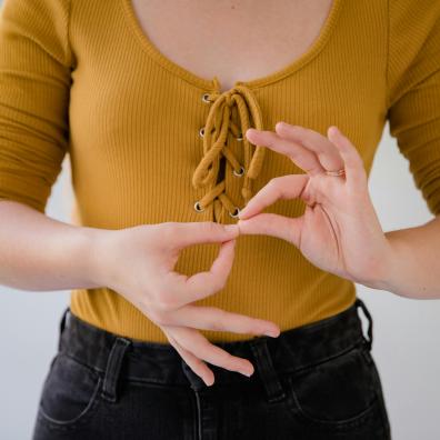 Gros plan sur le buste d'une femme qui fait le langage des signes