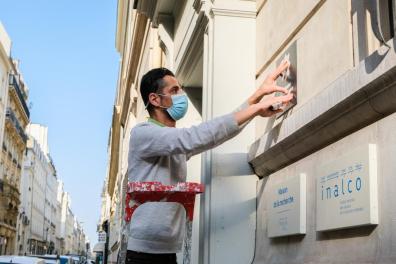 un homme accroche une plaque au mur 