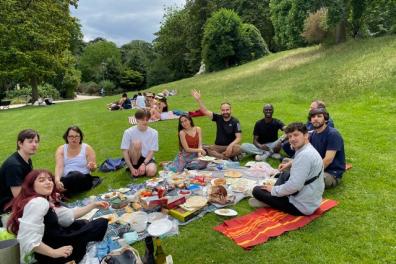 Des étudiants sont assis en rond dans l'herbe et sont entrain de pique-niquer