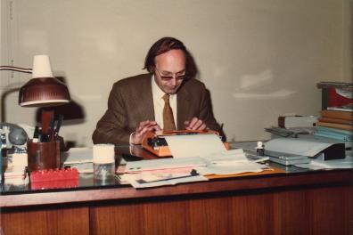 Homme en costume assis à un bureau et tapant sur une machine à écrire