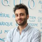 Andreas Guidi bras croisés devant le mur des langues de l'Inalco