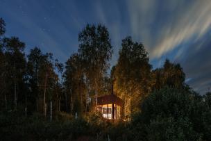 Cabane en bois éclairée au milieu d'une forêt 