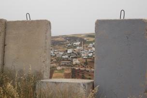 Vue d'un paysage d'habitations en Palestine avec en premier plan un mur 