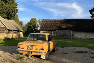 Photo d'une vieille voiture jaune avec en face et sur le côté gauche des vieilles bâtisses