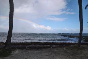 une plage avec un arc en ciel à l'horizon