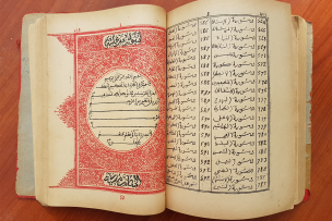 Ecritures arabes sur un livre ouvert sur deux pages avec sur la page de gauche une arabesque rouge