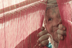 Une vieille dame entrouvre un rideau et regarde 