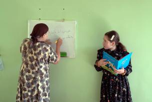 Une femme écrit sur un tableau en regardant l'autre qui tient un cahier 