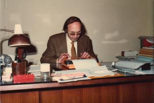 Homme en costume assis à un bureau et tapant sur une machine à écrire