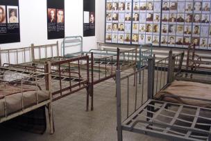 une pièce avec des lits en fer et des photos aux murs