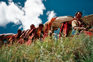 Des moines tibétains marchent dans la nature et portent sur leur dos un grand tissu