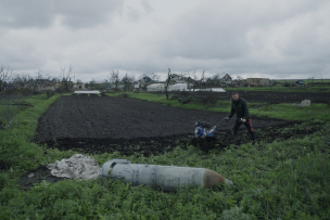 Un homme qui laboure un champ avec motoculteur et en premier plan une bombe