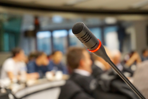 Photo d'un microphone au premier plan avec en arrière plan des personnes floues